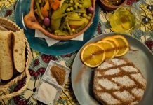 Plate with pastilla and orange slices, beside a mixed vegetable tagine and a basket of Moroccan breat