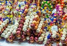 Brightly colored strands of onions and garlic, tied with ribbons