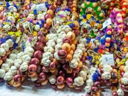 Brightly colored strands of onions and garlic, tied with ribbons